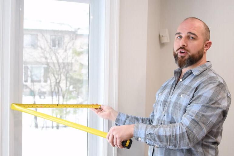 A Verdun sales representative shows holds a measuring tape to measure a window.
